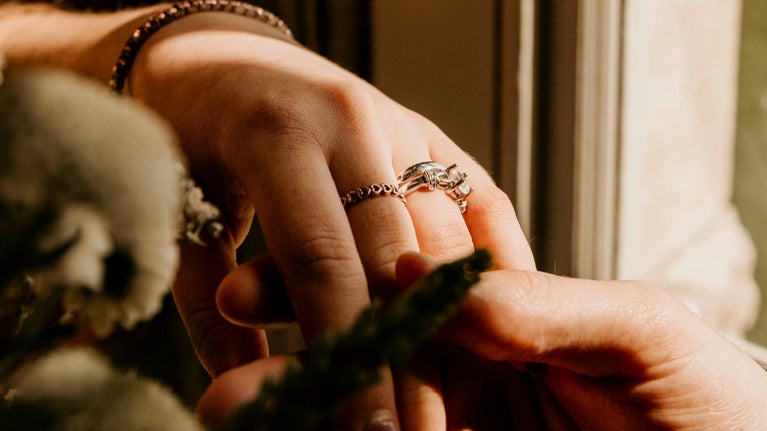 A close-up image of two hands with rings in focus.
